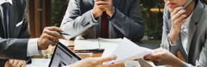People sitting around meeting table, papers and laptop on table
